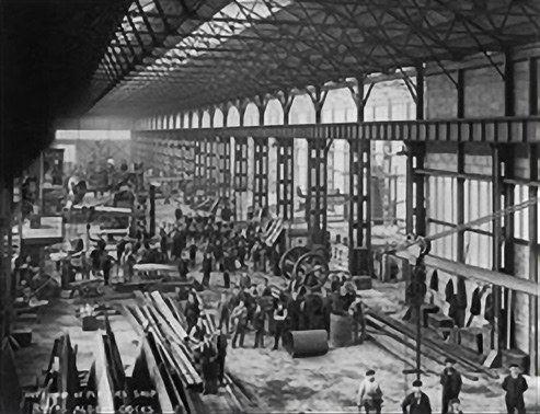 Fotografía histórica en blanco y negro del interior de un taller de ingeniería con numerosos trabajadores